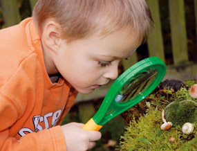 Kind das mit der Riesenlupe etwas untersucht